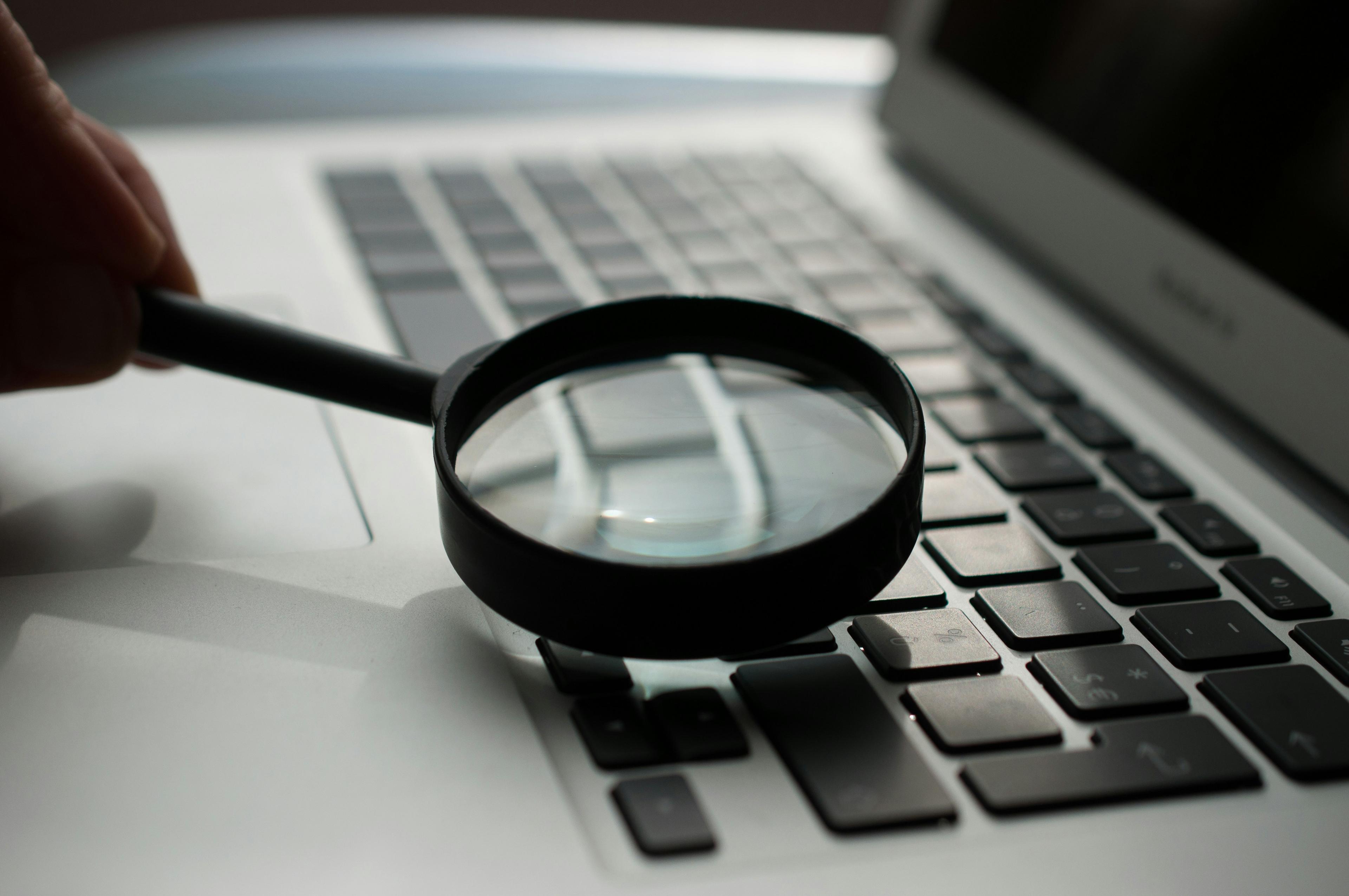 A magnifying glass next to a laptop