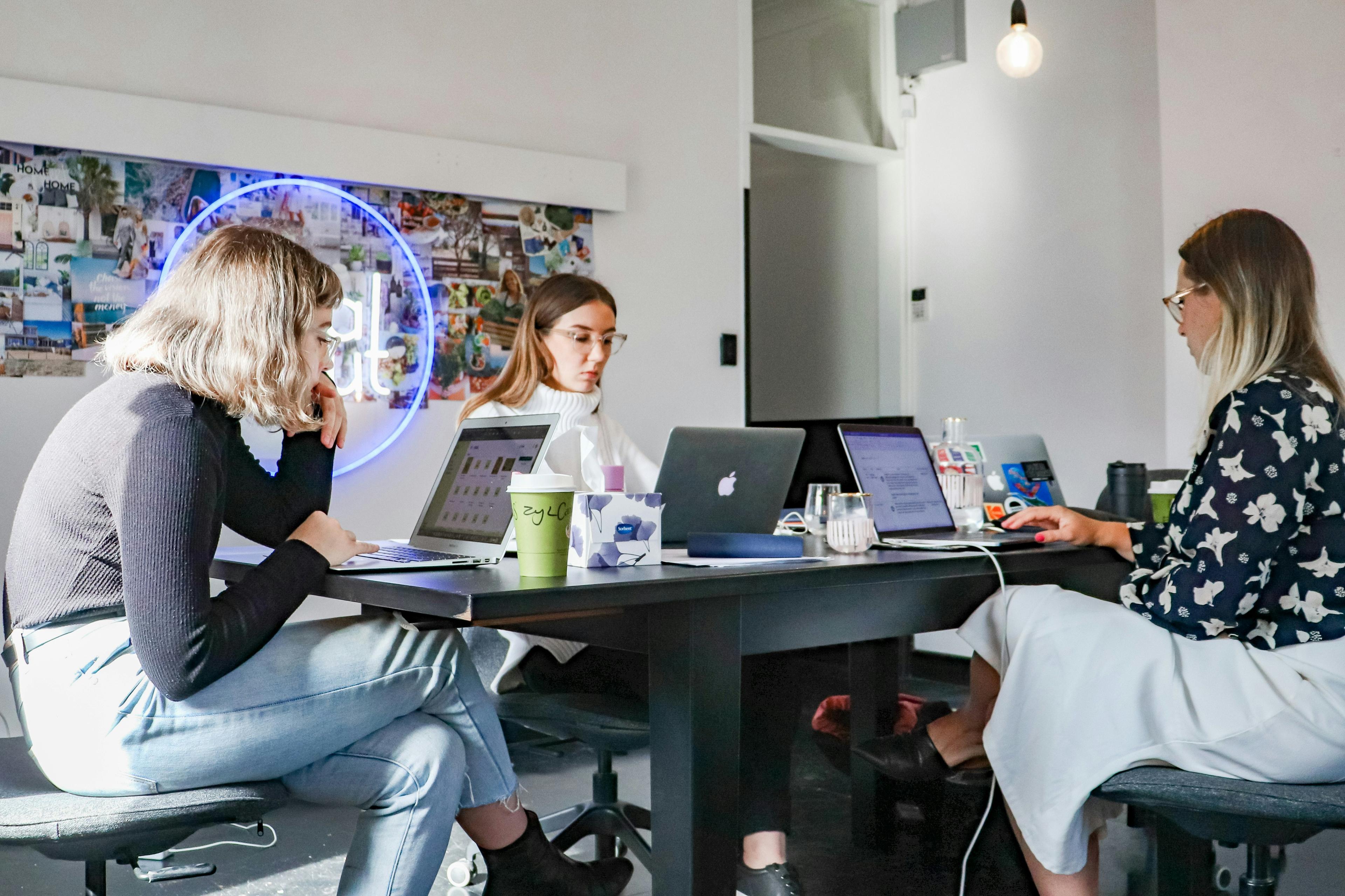 Three colleagues working together on laptops around a table